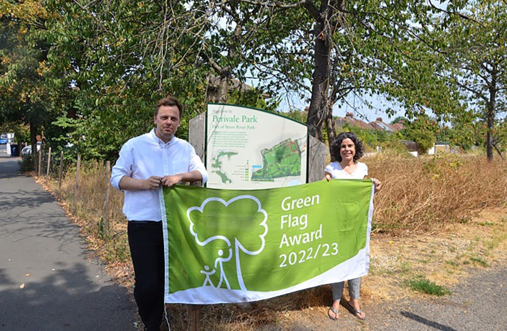 Two people standing next to a green banner.