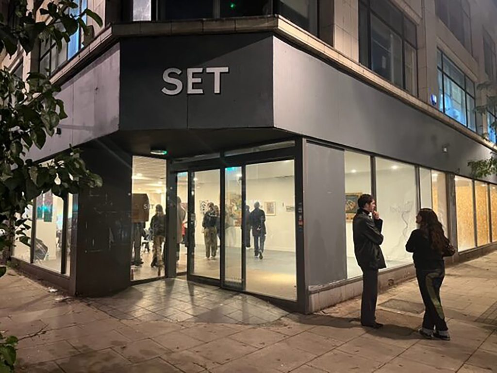 A group of people standing in front of a building at night.