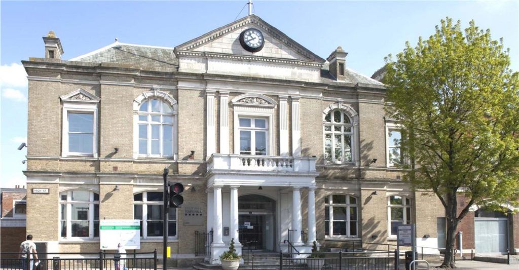 A large building with a clock in front of it.